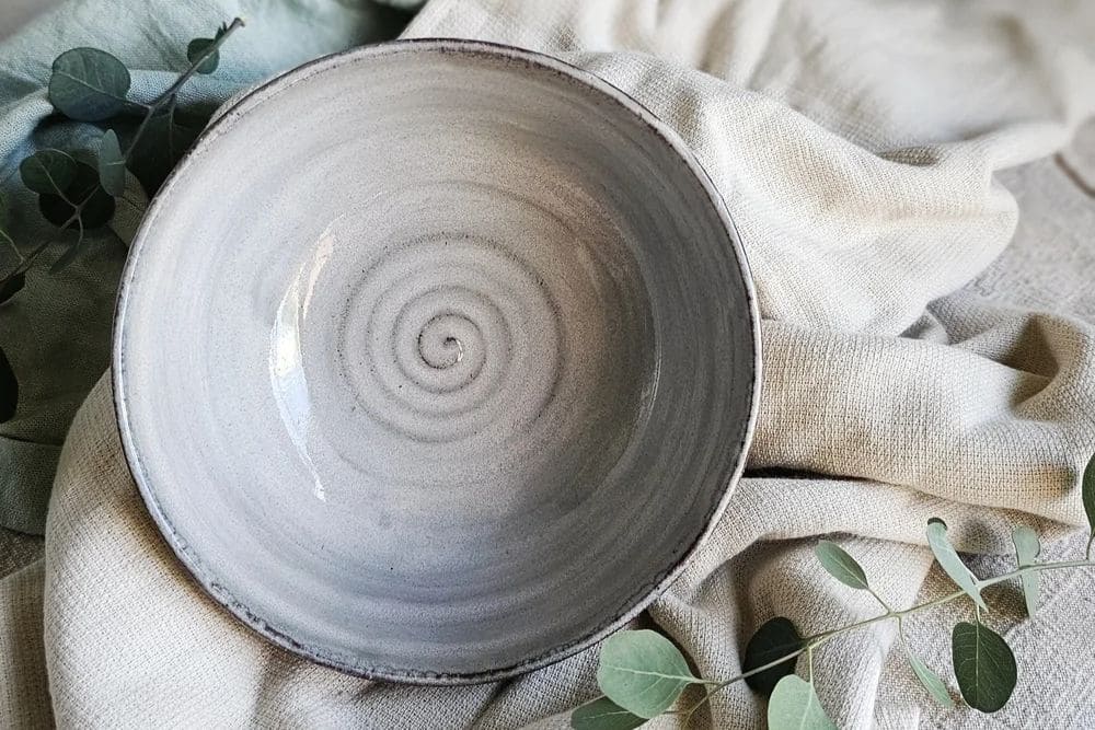 Whistle and Page grey ceramic spiral bowl on woven linen with eucalyptus leaves